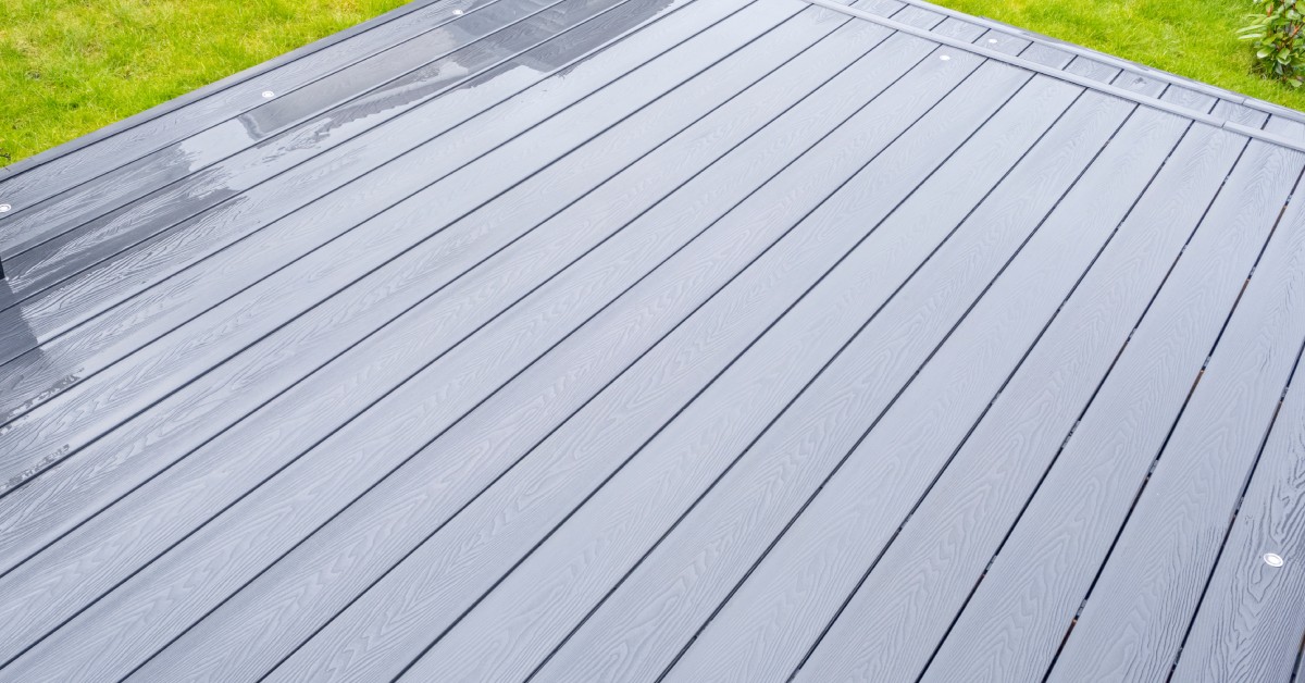 A gray deck made of composite material boards. The deck has a step leading down onto a green grass yard.