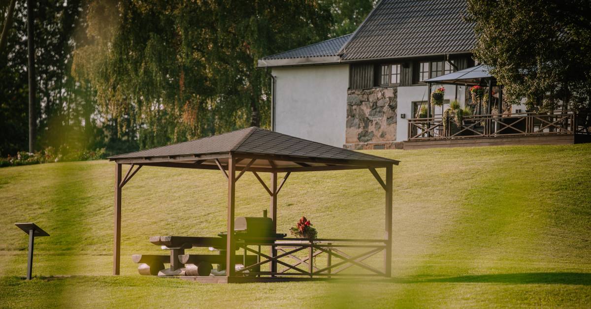 A home on a high hill with a gazebo on the deck and another situated at the base of the hill on flat ground.