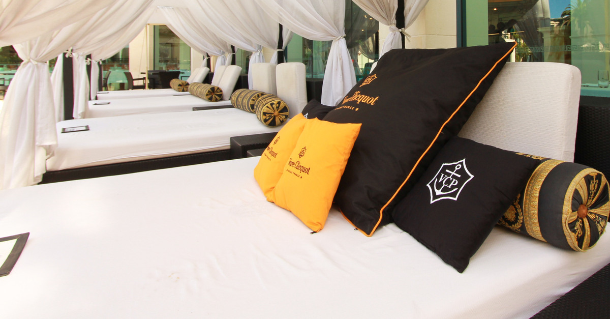 The inside of a cabana with a mirror on one wall and a large bed with luxurious black and gold pillows.